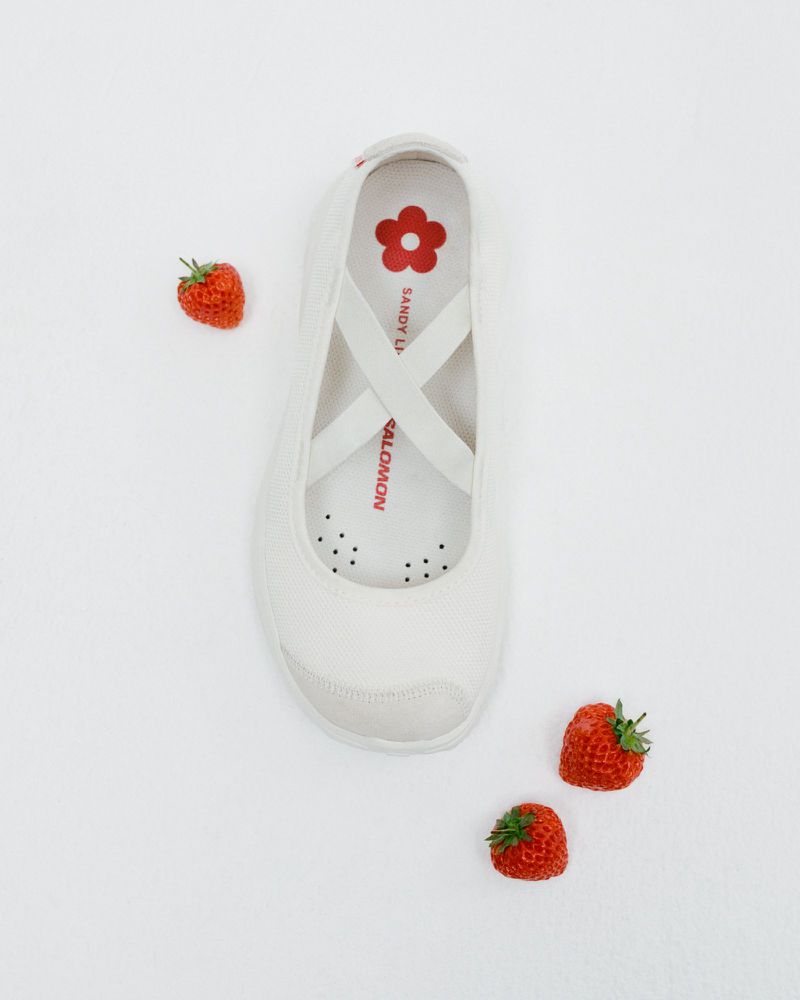 Elevated shot of a single white sneaker accented by fresh strawberries scattered on a light backdrop, evoking a fresh, summery aesthetic.