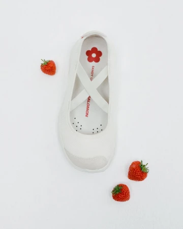 Elevated shot of a single white sneaker accented by fresh strawberries scattered on a light backdrop, evoking a fresh, summery aesthetic.