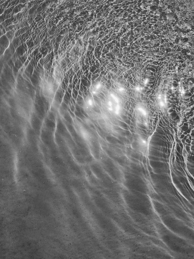 Monochrome image showcasing the interplay of light and shadow on rippling water, creating an abstract and textured water surface with unique patterns.