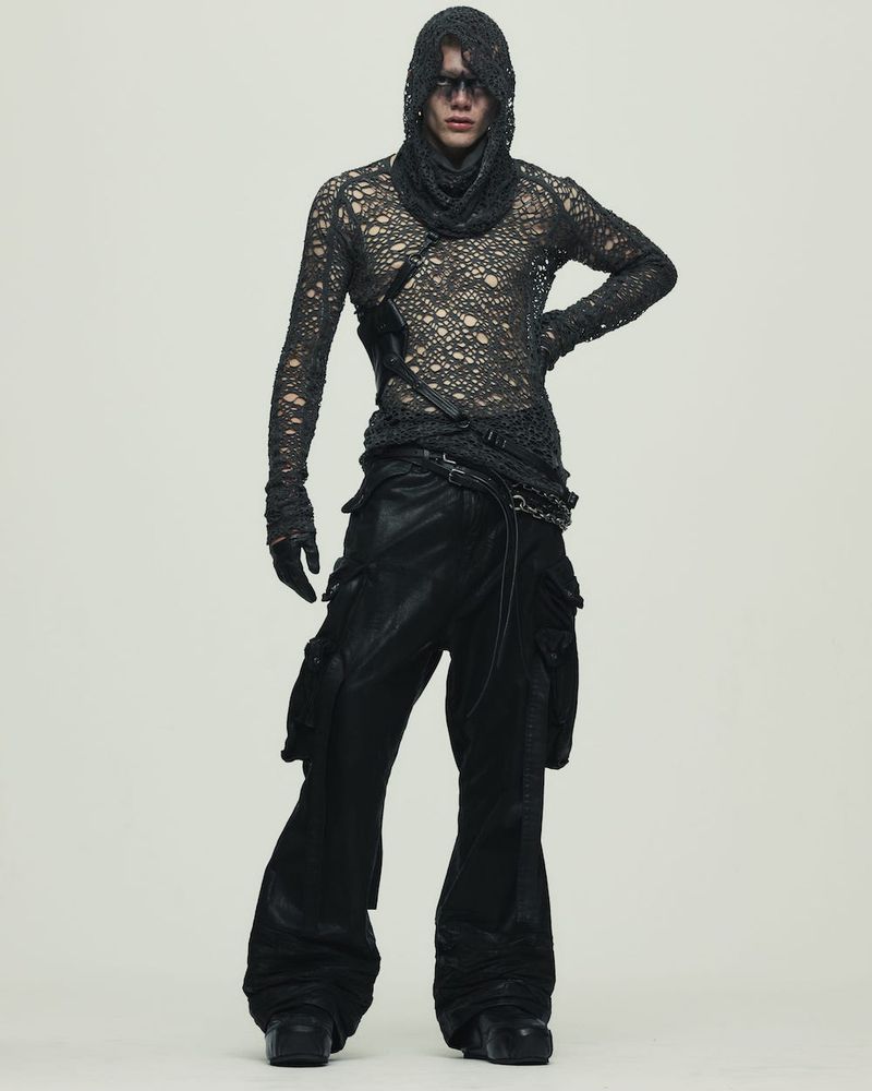Fashion model poses in a distressed long-sleeve top, cowl, and wide-leg cargo pants in a studio. Full-length shot with neutral background.