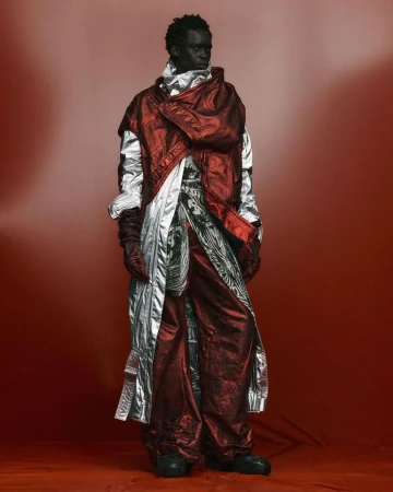 Full shot of a fashion model in an elaborate red and silver metallic outfit posing against a red gradient background, studio lighting.