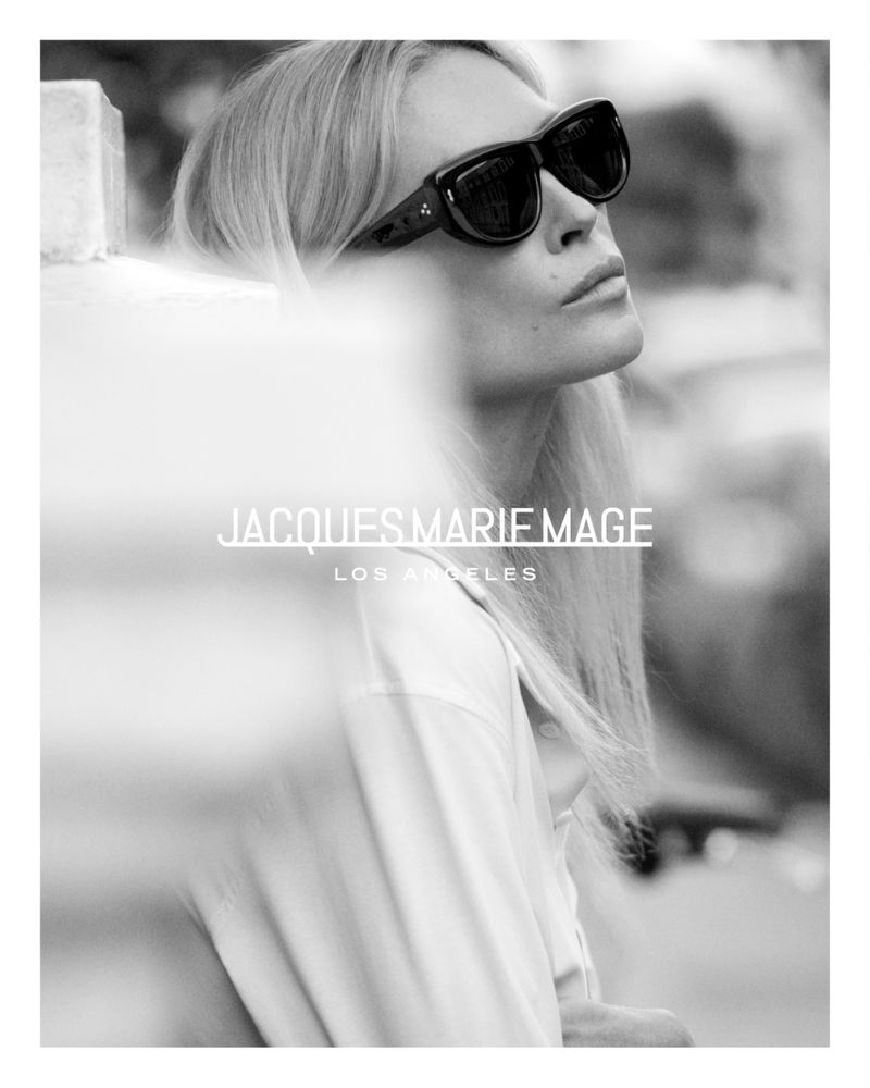 Black and white portrait of model Erin Wasson wearing bold black sunglasses and a light collared shirt.