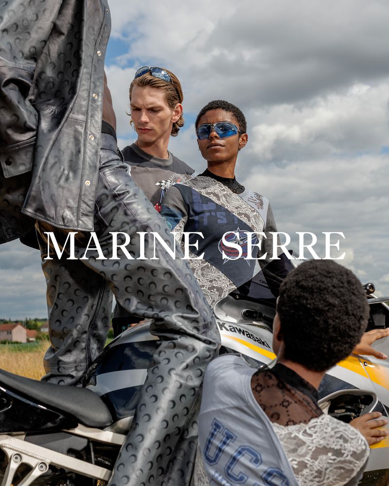 Models wearing Marine Serre apparel on a motorcycle against a cloudy sky and field backdrop, showcasing fashion and outdoor style.