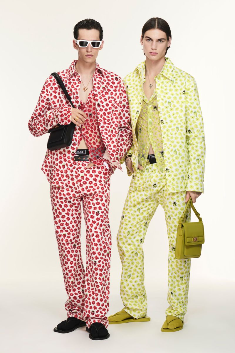 Two male models pose in patterned button-down shirts and matching pants against a neutral backdrop, showcasing contemporary fashion.