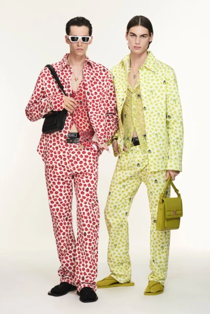 Two male models pose in patterned button-down shirts and matching pants against a neutral backdrop, showcasing contemporary fashion.