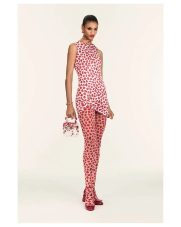 Fashion model wears a red and white dress and tights with a matching purse in a studio shot against a white backdrop. 