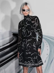 Model Patricia Zajac in a black and white printed high-neck dress and sunglasses against a graphic curved road backdrop.