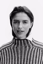 Close-up portrait of a woman wearing a black and white striped sweater against a plain white background