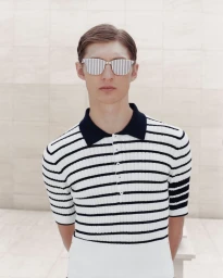 Robbie Lyons wears a black and white striped ribbed knit polo shirt and striped sunglasses for Thom Browne S/S 24.