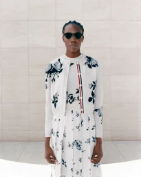 Robbie Lyons wears a floral Thom Browne cardigan set and sunglasses against a stone tile wall.