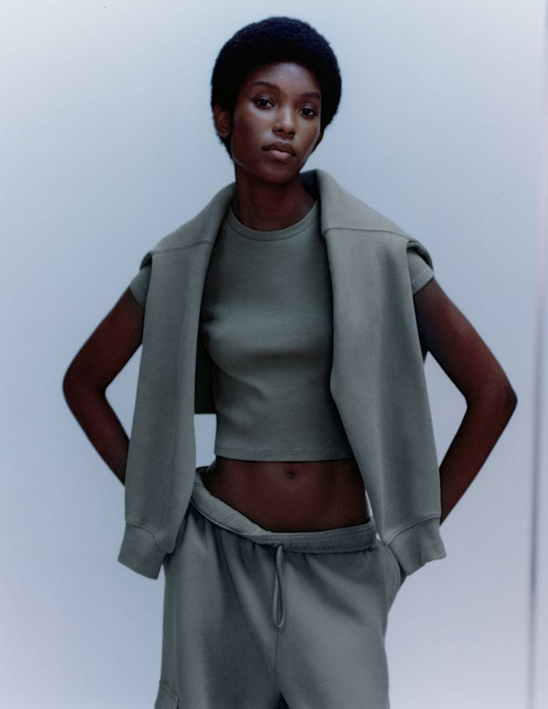 Fashionable African-American woman in a matching earth-tone sweat suit posing against a white studio backdrop with natural lighting.