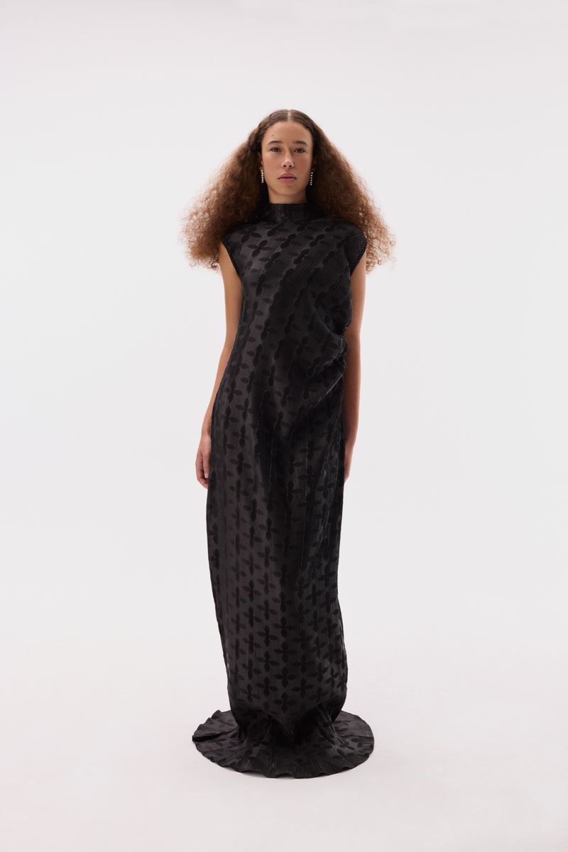 Adult female posing in long black dress, studio lit on white background. Fashion-forward editorial shot with minimalist aesthetic.