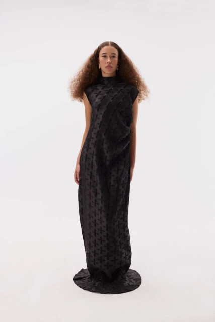 Adult female posing in long black dress, studio lit on white background. Fashion-forward editorial shot with minimalist aesthetic.