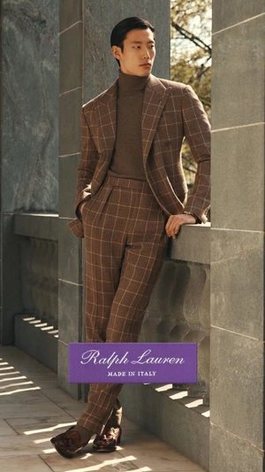Model Juhyung Kang in a brown windowpane plaid suit and turtleneck leaning against a stone terrace balustrade for Ralph Lauren.