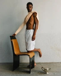 Model Checkne Doucoure posing with a chair in Federico Curradi S/S 25 men's lookbook