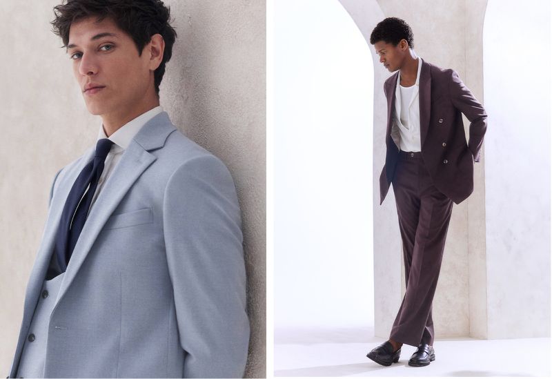 Two men model suits in a studio setting, one in a light blue suit with a tie and the other in a brown suit.
