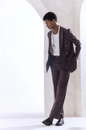 Model O'Shea Robertson in a plum double-breasted suit standing beneath arched architectural columns by photographer Simon Lipman.
