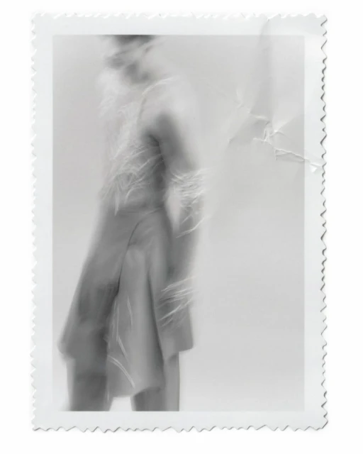 Monochrome photograph of an adult wearing a fringed jacket in a blurred motion, with a decorative white border and textured background.