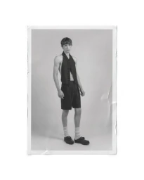 Monochrome portrait of a model standing in a black halter-neck vest and tailored shorts against a studio backdrop.