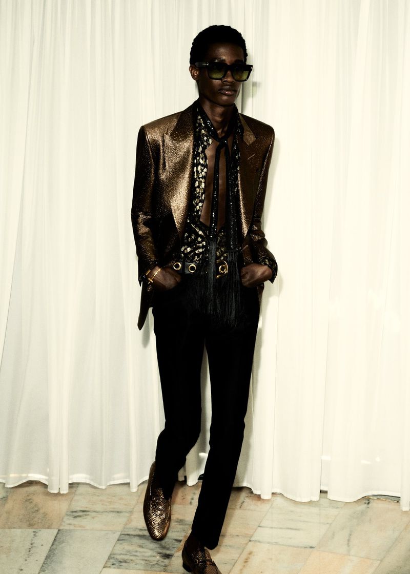 Model Daniel Awaridhe wearing a metallic bronze blazer, tinted sunglasses, and black trousers for the Tom Ford S/S 25 lookbook.