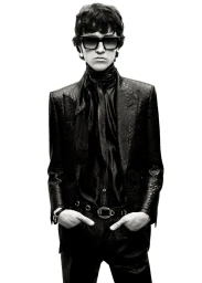 Daniel Awaridhe wearing dark sunglasses, a textured black blazer, and a silk neck scarf against a white background for Tom Ford.