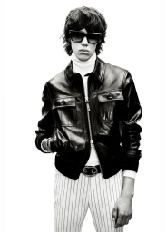 Model wearing a black leather jacket, white turtleneck, and striped trousers against a plain white background for Tom Ford.