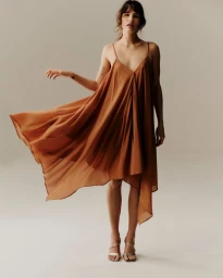 Model in a flowing brown slip dress standing against a neutral background for Primark.