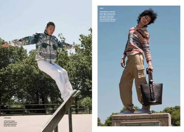 Two men modelling designer menswear outdoors, one balancing on a rail and the other holding a leather tote on a concrete block against a clear sky