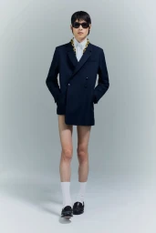 Model in black suit and baseball cap posing against a neutral grey studio background for Random Identities