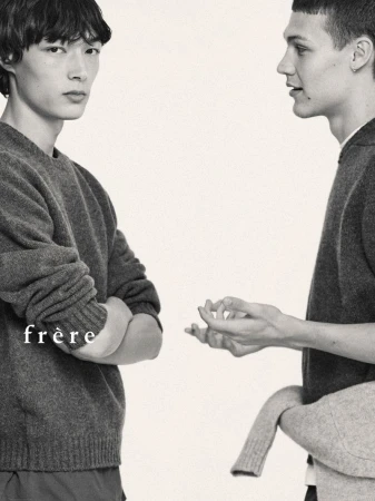 Two adult male models wearing sweaters in a studio setting, showcasing minimalist fashion and neutral tones.