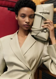 Model wearing neutral beige blazer holding light beige leather handbag in Oroton campaign by Victoria Zschommler