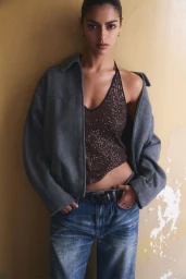 Model in grey jacket and blue jeans posing against a weathered textured wall for Pull & Bear campaign