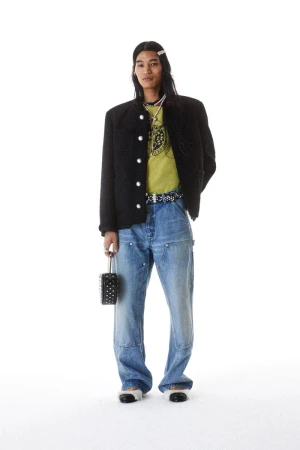 Model Kyosuke Akiyoshi posing in a black buttoned jacket and relaxed blue denim jeans against a white background for Ambush S/S 25.