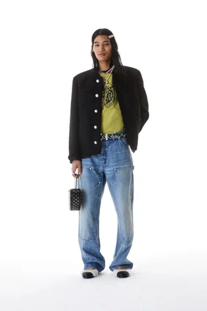 Model Kyosuke Akiyoshi posing in a black buttoned jacket and relaxed blue denim jeans against a white background for Ambush S/S 25.