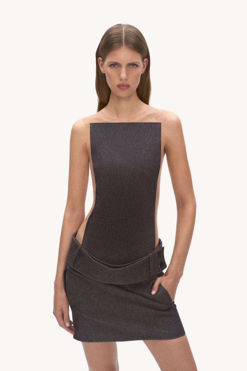 Fashion shot of an adult female model wearing a dark gray denim dress in a bright photo studio with a neutral background.