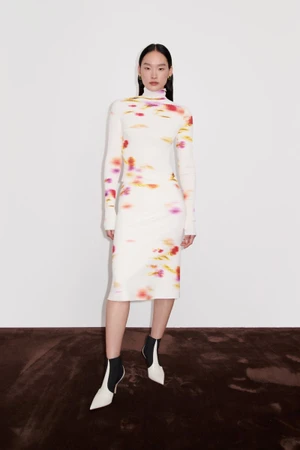 Model Yoonmi Sun poses in a printed white turtleneck midi dress and two-tone pointed ankle boots for Ferragamo Resort 2025.