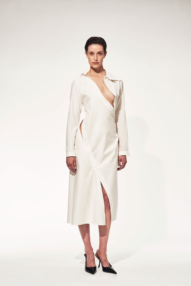 A single female model poses in a white midi dress with a plunging neckline and slit, complemented by black high heels in a studio shot.
