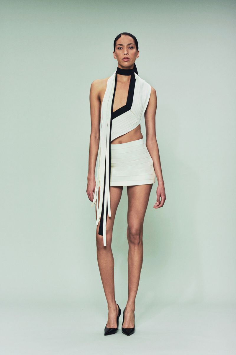 A stylish adult woman is posing in a black and white outfit in a studio, with a clean backdrop that brings the focus to fashion and form.