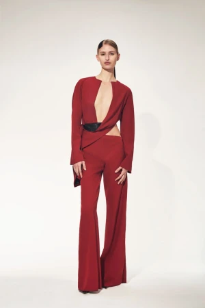 Model Tyvanni Osaheni wearing a crimson cut-out top and wide-leg trousers against a white backdrop for Max Zara Sterck.