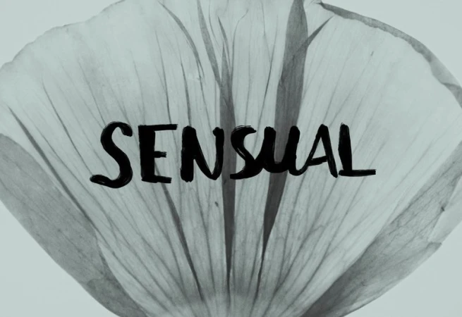Monochrome image of a translucent flower petal with visible veins, overlaid with the word 'SENSUAL' in bold, black, handwritten-style font.