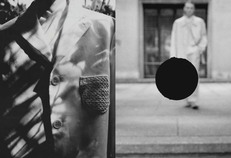 Monochrome image with a tailored jacket featuring a knitted pocket and a blurred figure in a coat walking in the background.