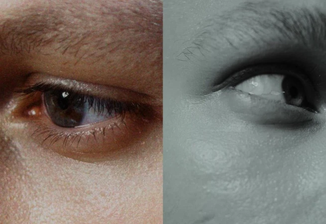 Macro shot showing two human eyes, one in color with brown iris, the other eye in grayscale, side-by-side, close-up of human face.