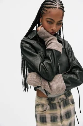 Model with braided hair wearing a dark leather jacket and plaid jeans against a bright white background