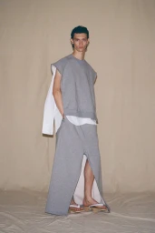 Model wearing a grey sleeveless top and matching maxi skirt standing against a textured backdrop for Setchu S/S 25