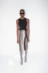 Model wearing dark sunglasses, patterned knit top, and striped skirt against a plain white background