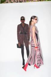 Two female models in designer resort wear posing against a white studio backdrop, showcasing patterned knitwear and accessories.