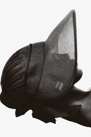 Model wearing a black mesh sun hat against a plain light background for H&M summer 2024 lookbook