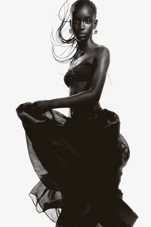 Model Maty Fall wearing black swimwear and hoop earrings against a white seamless background for H&M.