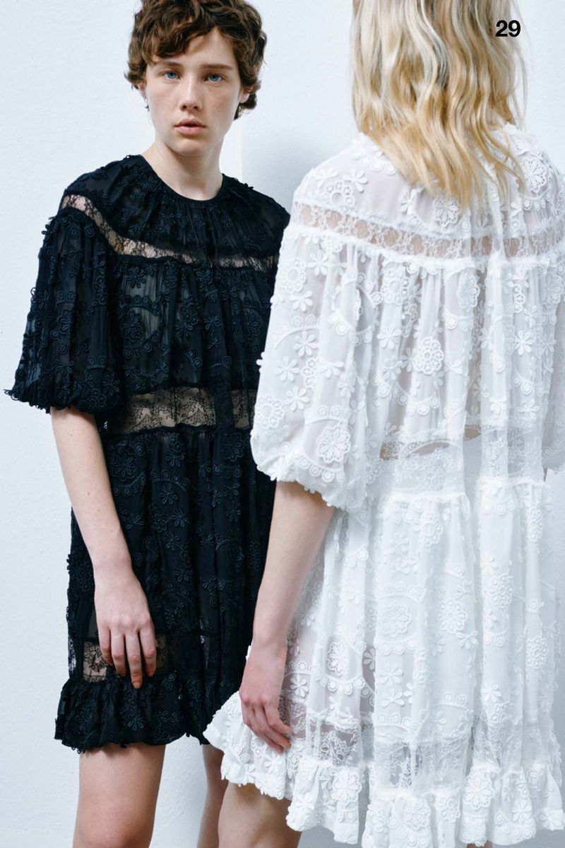 Two fashion models showcase elegant lace dresses in black and white, posing against a clean white backdrop in a studio setting.