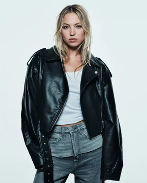Model Lila Moss wearing a black leather jacket and white top for Zara against a white backdrop